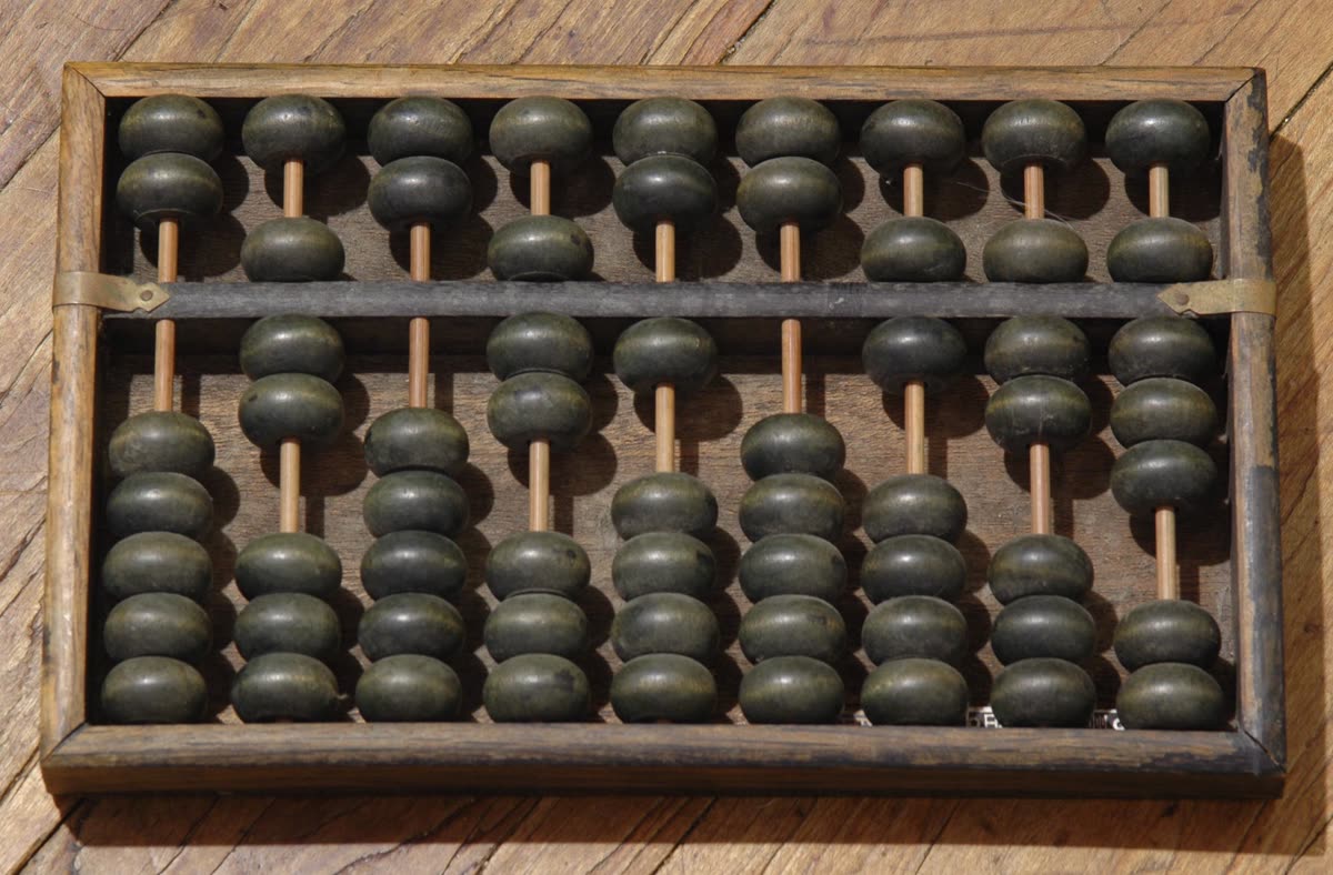 Traditional Chinese suanpan abacus with wooden frame and beads on horizontal rods, showing the classic 2/5 layout — two beads above the dividing bar, five below